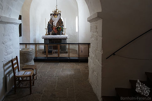 Der Altarraum der Rundkirche von Olsker mit Kronleuchter und Taufstein, Insel Bornholm, Daenemark
